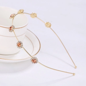 Detailed view of rhinestone sunflower headband with amber crystal on a white cup