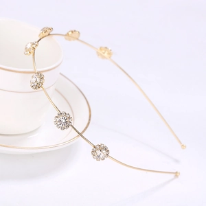 Elegant gold metal headband featuring sparkling rhinestone sun flowers by ceramic cup