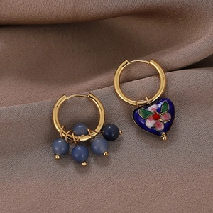 Macro detail of asymmetric heart earring with blue enamel and floral cloisonne pattern