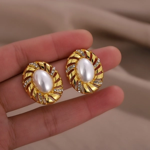 Vintage gold plated oval pearl earrings with sparkling crystal accents held by hand