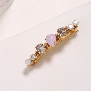 Détail d'une barrette dorée avec strass rose en goutte et cristaux marron rectangulaires