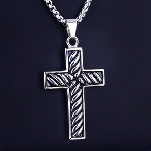 Macro view of a silver stainless steel cross pendant with detailed rope texture on a box chain