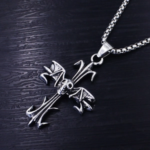 Macro shot of silver stainless steel gothic cross pendant with skull and bat wing details