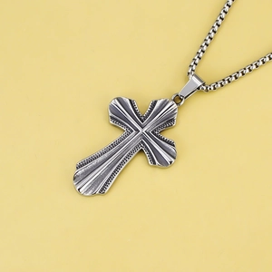 Détail du pendentif croix punk argenté avec texture radiale et bords perlés sur chaîne box
