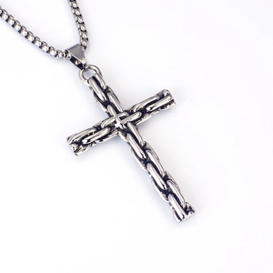 Vue macro d'un pendentif croix punk vintage en acier inoxydable avec texture tressée