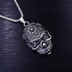 Détail d'un pendentif crâne vintage en acier avec gravure mandala et chaîne box