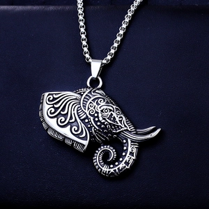 Macro detail of vintage silver elephant head pendant with tribal carvings on steel chain