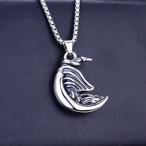 Macro detail of vintage dragon moon pendant with embossed texture and silver box chain