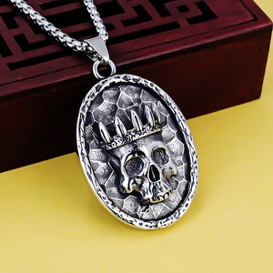 Macro detail of retro stainless steel skull crown pendant on a round box chain