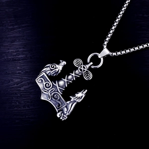Macro shot of Viking Mjolnir pendant featuring wolf and crow totems in aged stainless steel