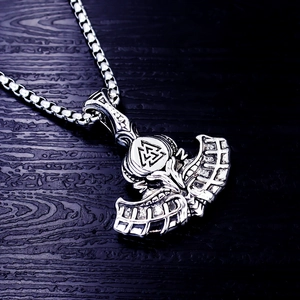 Macro detail of silver stainless steel Viking axe pendant with Valknut symbol on wood