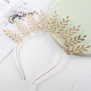 Close-up of golden leaf crown headpiece on a white textured background with props
