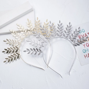 Detailed view of elegant gold and silver leaf bridal headbands on a white surface