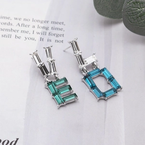 Asymmetric silver letter earrings with green and blue baguette-cut crystals