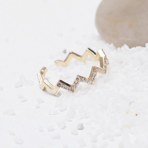 Adjustable gold wavy ring with sparkling micro-paved zircons on a white pebble background