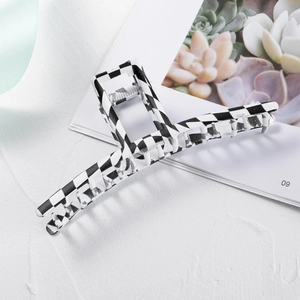 Classic black and white checkered hair claw clip made of resin on a textured white background