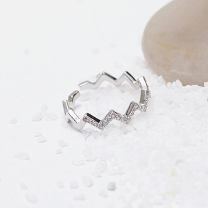 Macro shot of silver-tone zigzag ring with white zircon stones set in white fine sand