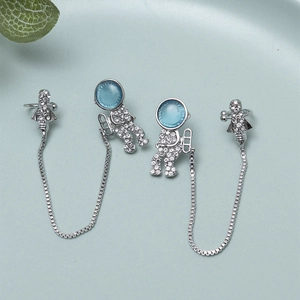 Detail of silver asymmetric astronaut and rocket earrings with blue opal helmet and rhinestones