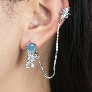 Detail of astronaut stud and spaceship cuff connected by a silver chain with blue gems
