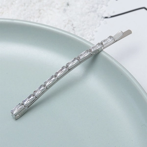 Elegant silver hair clip with rectangular zircons on a blue ceramic plate for women