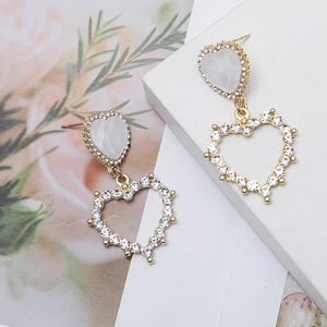 Gros plan de boucles d'oreilles cœur dorées avec strass brillants sur un socle élégant