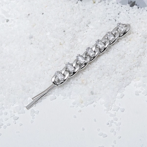 Silver Cuban chain hair clip with sparkling zircons on a white sand background