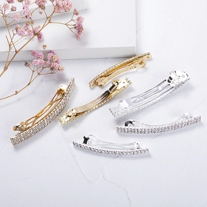 Detail view of sparkling gold and silver rhinestone hair clips on white marble base
