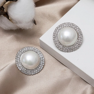 Macro shot of luxury round pearl earrings with sparkling crystal accents on silk