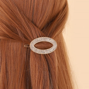 Barrette à cheveux ovale dorée avec strass multicouches sur de longs cheveux bruns