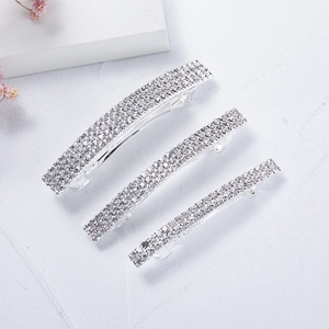 Three-piece set of silver spring hair clips with sparkling white rhinestones on marble