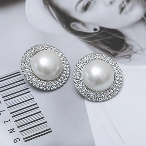 Detailed view of oversized pearl earrings with crystal halo on a fashion magazine