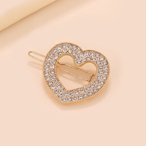 Barrette en forme de cœur dorée avec strass scintillants sur un fond crème épuré