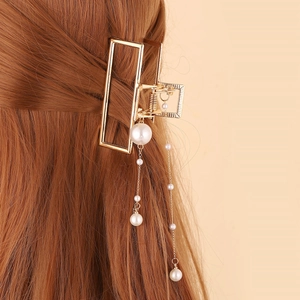 Détail d'une pince à cheveux dorée avec pampilles de perles élégantes sur cheveux bruns