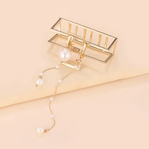 Détail de la pince à cheveux dorée avec d'élégantes chaînes de perles blanches