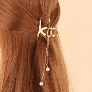Détail d'une pince à cheveux dorée avec glands en perles sur de longs cheveux bruns