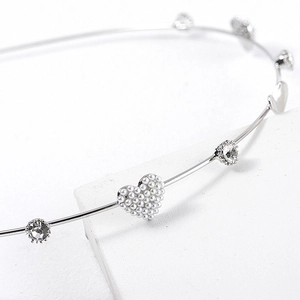 Close-up of a silver metal headband featuring pearl hearts and sparkling rhinestones