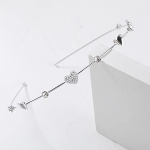 Detailed view of a silver metal headband with pearl hearts and sparkling rhinestones