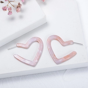 Pink marbled resin heart hoop earrings displayed on a white decorative stone base
