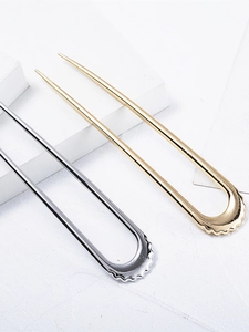 Dettaglio macro di forcine a U in oro e argento con elegante bordo metallico a onde