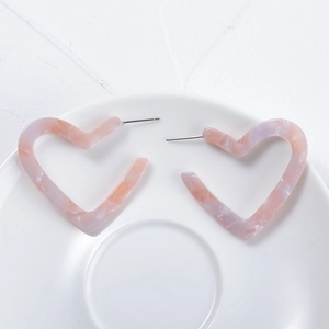 Pink marbled resin heart-shaped hoop earrings on a minimalist white ceramic tray