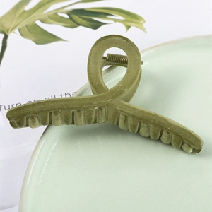 Pince à cheveux élégante en velours vert olive pour femme sur une assiette en céramique