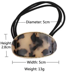 Oval acetate hair tie with tortoiseshell pattern and gold metal frame on black elastic rope
