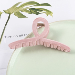 Pince à cheveux en velours rose avec design croisé sur une plaque en céramique