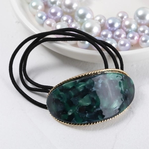 Close-up of green marble oval resin hair tie with golden twisted metal edge details