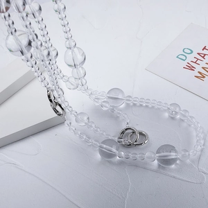 Elegant clear acrylic beaded necklace with silver metal clasps on a white textured background