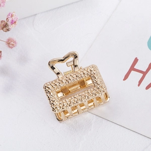 Close-up of golden rectangular metal hair claw with textured finish and heart detail
