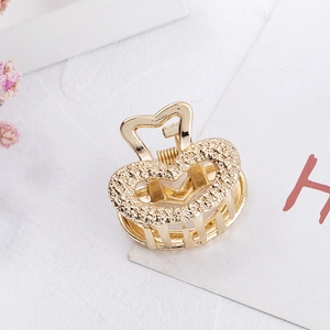 Golden heart-shaped alloy mini hair claw clip with textured finish on white background