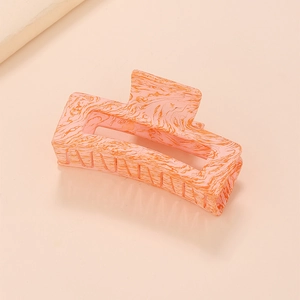 Détail de la pince à cheveux en résine à motif marbré rose et orange avec design géométrique