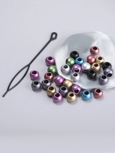 Macro shot of colorful metallic dreadlock beads with a black threading tool for hair styling
