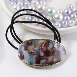 Close-up of oval acetate hair tie with purple marble texture and gold twisted metal frame